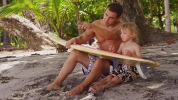 pai e filho na praia com prancha de surf. filmado em vermelho épico para alta qualidade 4k, uhd, resolução ultra hd. video