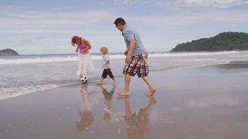 Familie, die zusammen Fußball am Strand tritt, Zeitlupe. Aufnahme auf rotem Epos für hochwertige 4k-, UHD- und Ultra-HD-Auflösung. video