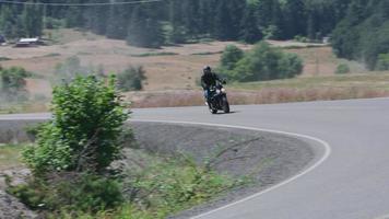 Tracking shot of man riding motorcycle on country road.  Fully released for commercial use. video