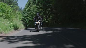 tracking shot van man rijden motorfiets op landweg. volledig vrijgegeven voor commercieel gebruik. video