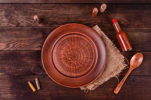 Plate, spoon, spices and other kitchen accessories on a dark wooden background photo