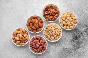 Assortment of nuts in white saucers on a concrete background photo