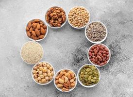Assortment of nuts in white saucers on a concrete background photo