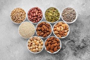 Assortment of nuts in white saucers on a concrete background photo