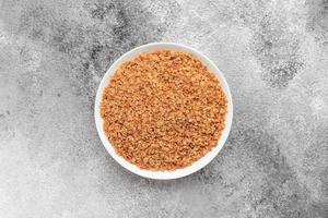 Buckwheat cereal in a white saucer on a gray concrete background photo