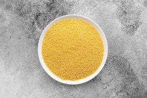 Couscous in a white saucer on a gray concrete background