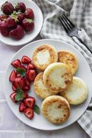 Cottage cheese pancakes, ricotta fritters on ceramic plate with  fresh strawberry.