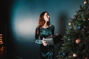 hermosa chica con una caja de regalo cerca del árbol de navidad foto