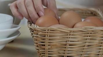 Koch stapelt frische Eier im Korb auf Holztisch vor dem Kochen. video