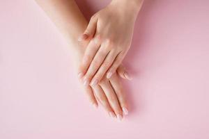 hermosas manos femeninas sobre fondo rosa. concepto de spa y cuidado corporal. imagen para publicidad.