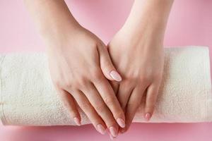 Spa procedure for nail care in a beauty salon. Female hands and tools for manicure on pink background. Bodycare concept. photo