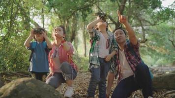 la familia trajo a dos hijos de excursión usando binoculares para aprender la naturaleza durante las vacaciones en el centro de estudio de la naturaleza. video