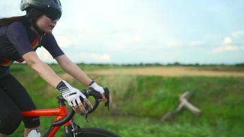 vista laterale tracking.donne asiatiche ciclista arancione che indossa il casco protettivo allenamento per l'esercizio a cavallo veloce sulle strade al di fuori della città video