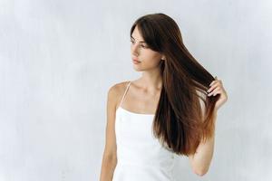 tan libre como el viento. retrato de mujer linda encantadora está de pie y mirando a otro lado mientras disfruta de la calidad de su cabello largo. fondo aislado foto