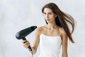 Retrato de mujer alegre que sopla el viento en el cabello después de tomar una ducha. ella mirando a la cámara con expresión tranquila. concepto de apariencia de mujer foto