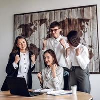 A group of business people working in an office at a joint meeting make a winning gesture photo