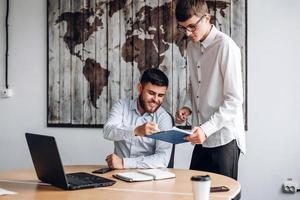 Young guy in glasses gives his boss documents to sign photo