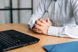 Businessman clasped hands on desk, working on computer photo