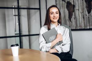 Pretty brunette with documents in her and cups of coffee, working in the official photo