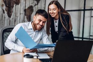 Un gerente sonriente y su asistente trabajan en la oficina. foto