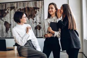 Beautiful businesswomen discuss and whisper to each other photo