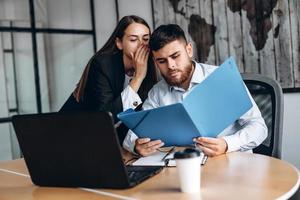 Pretty girl whispers in the ear to her employee photo