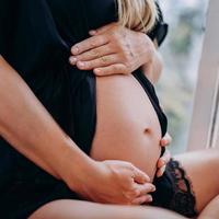 A pregnant woman hugs her tummy