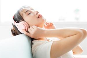 Portrait of young girl sitting on sofa reclining back and tanaj enjoying music photo