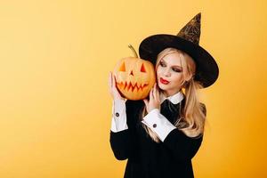 Retrato de mujer sobre un fondo amarillo sosteniendo la calabaza y mirando sonriendo foto