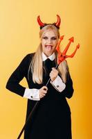 devil woman standing against a yellow background and showing the tongue. - Vertical image photo