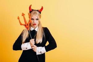 devil woman standing against a yellow background with menacing look. photo