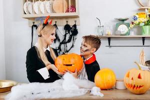 madre e hijo sosteniendo una calabaza durante los preparativos para halloween. foto