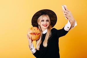 Mujer alegre tomar una foto selfie retrato sobre un fondo amarillo sosteniendo calabaza