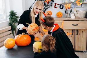 Mother and children holding pumpkin and have funny time at home. -Halloween concept photo