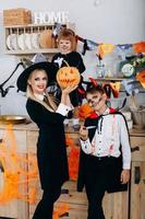 Madre e hijos en la cocina de pie en disfraces y mirando a la cámara - concepto de halloween foto