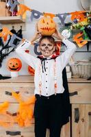 Niño de pie en traje de mascarada sosteniendo una calabaza en la cabeza - concepto de Halloween foto