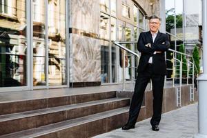 Full length portrait of businessman standing next business building and smiling - Image photo