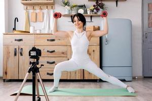 Entrenamiento en linea. alegre joven haciendo ejercicios mientras graba un video de un entrenamiento foto