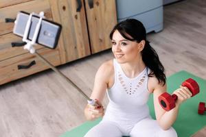 Young, attractive girl with a dumbbell in her hand makes a photo