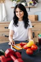 una joven morena bien arreglada prepara comidas saludables después de un entrenamiento foto