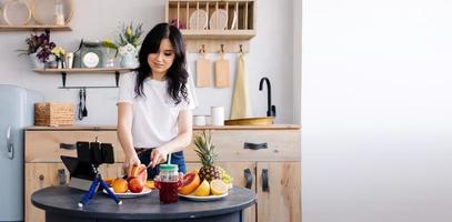 hermosa morena prepara batido de frutas en casa en la cocina y elimina el proceso de cocción para su canal foto