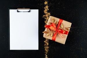 Christmas wish list with empty space for text on black background with golden star and gift. photo