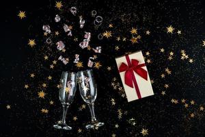 In anticipation of the holiday. Glasses, gold sequins and candies on a black background. photo