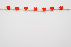 Corazón de papel rojo colgado en el tendedero en la pared blanca. lugar para publicidad foto