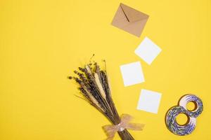 white sheets, envelope, figure eight, a bunch of dry grass lie  on a yellow background photo