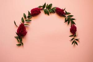 Arch of fresh flowers lie on a pink background - Copy space photo