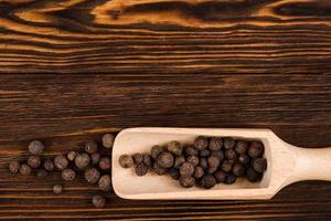 Spices, black pepper lie on wooden background photo