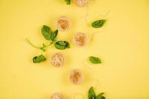 Pasta and basil closeup. Top view.On the yellow background. photo