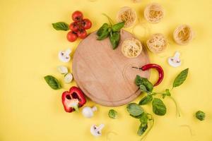 Pasta on a wooden board, vegetables. Top view. Copy space for text. photo