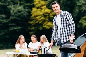 Young guy standing with the lid of the barbecue in his hand and looking at the camera photo